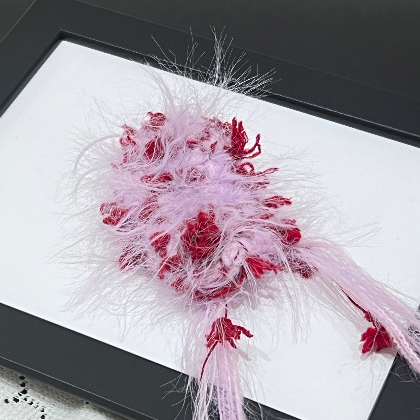 Close-up macro detail of pastel lilac crimson petal layered multi-strand blended fiber on black display frame