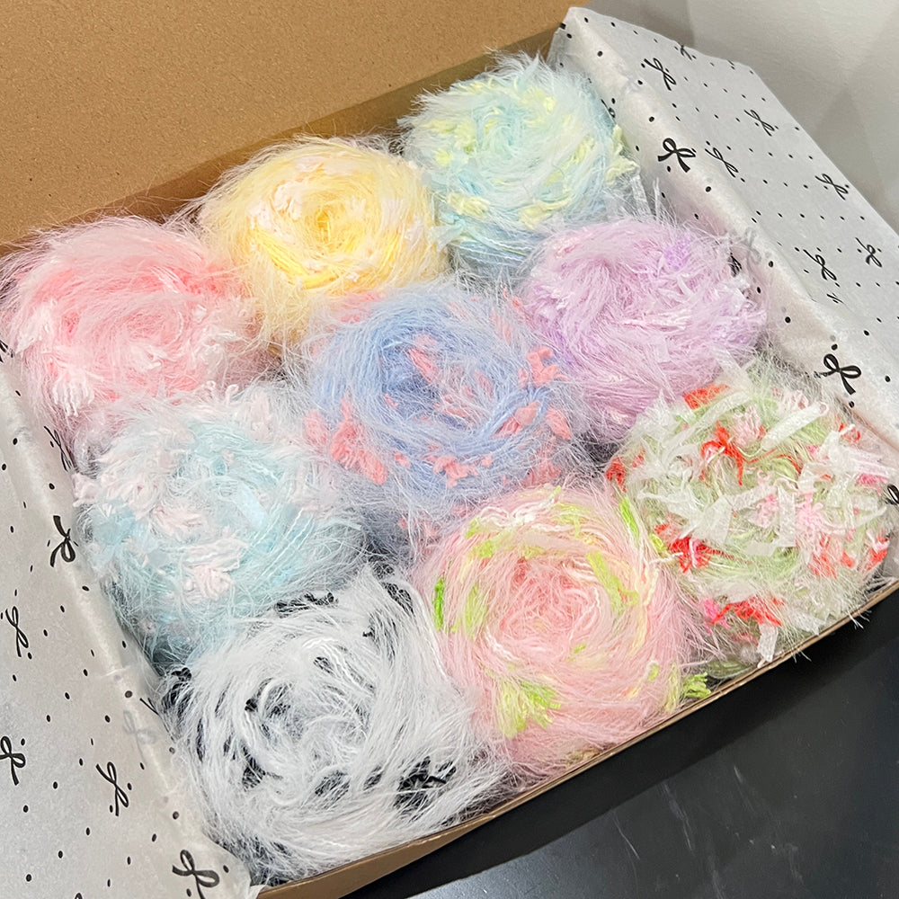 Open gift box with 9 varied pastel blended yarn cakes, assorted sky blue, pale yellow, blush pink, lilac, mint and multi-tonal floral yarn inside decorative gift box