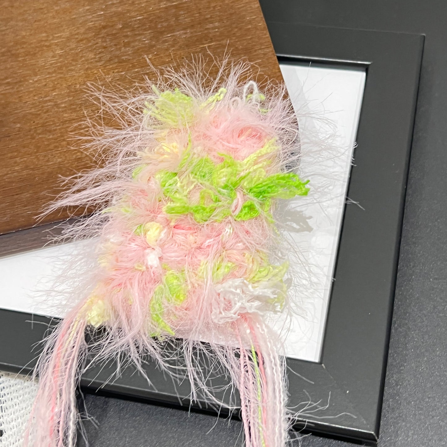 Close-up detail of pastel pink lime petal layered multi-strand blended fiber texture on black display frame