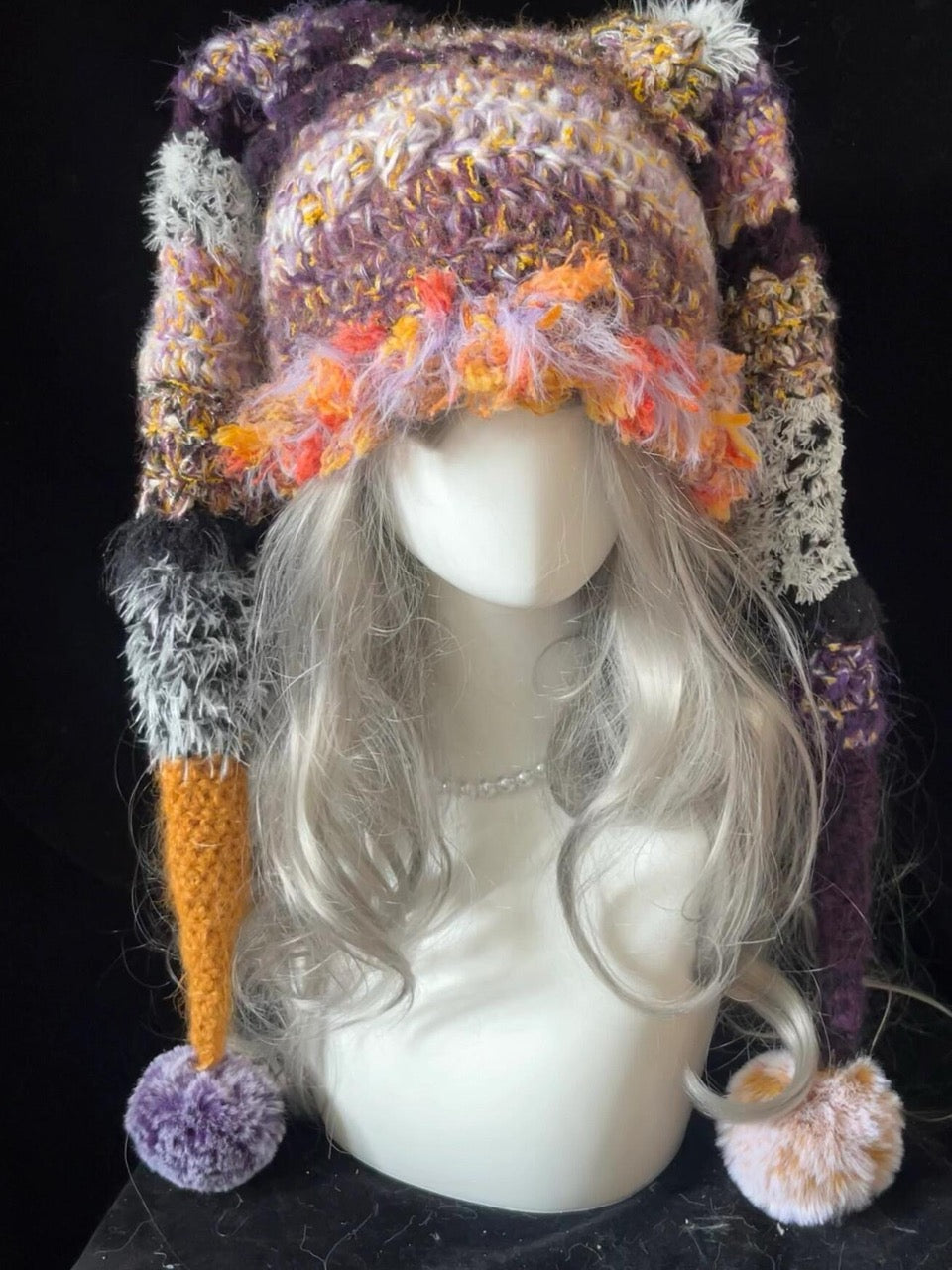handmade crochet goblincore jester hat in purple and orange shaggy textured yarn with long drooping points and pompom tips, fantasy festival headwear
