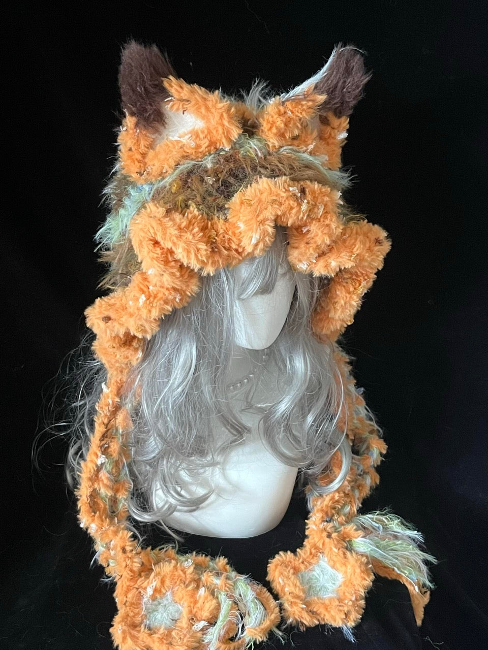 handmade crochet fairycore fox ear hood with orange and pink floral shaggy texture, tall pointed ears and long braided ties, a cozy winter cosplay accessory
