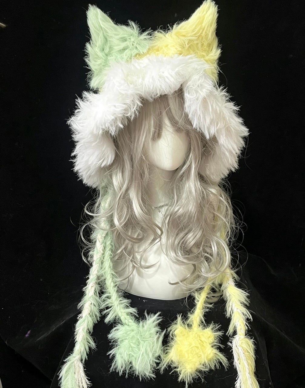 handmade crochet cottagecore fox ear hood in soft mint green and pale yellow shaggy yarn, featuring tall animal ears and long ties with fluffy pompom ends