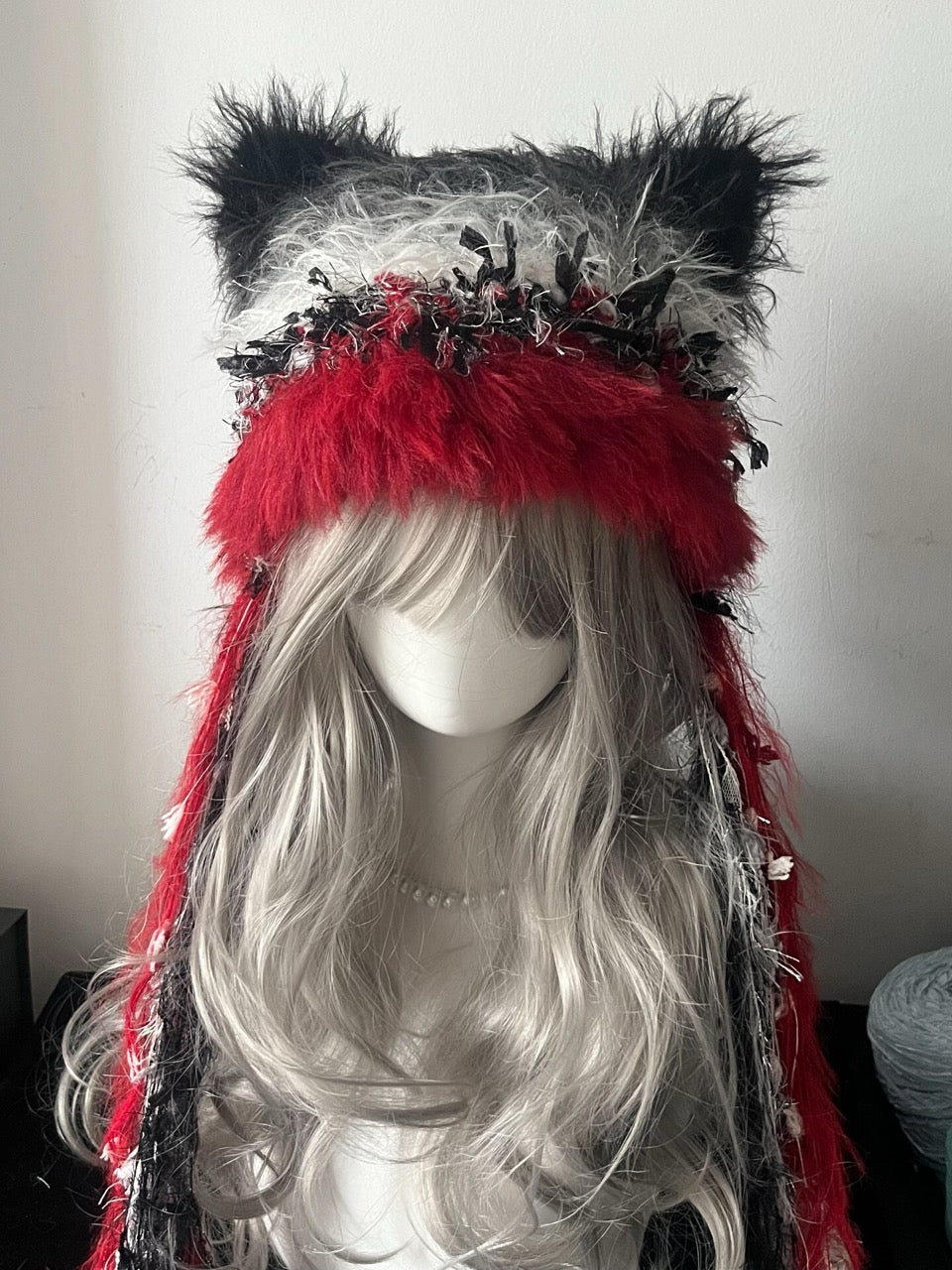 handmade crochet gothic cat ear hood in red, black, and gray shaggy faux fur with floral textured details and long tassels, an alternative cosplay accessory for winter