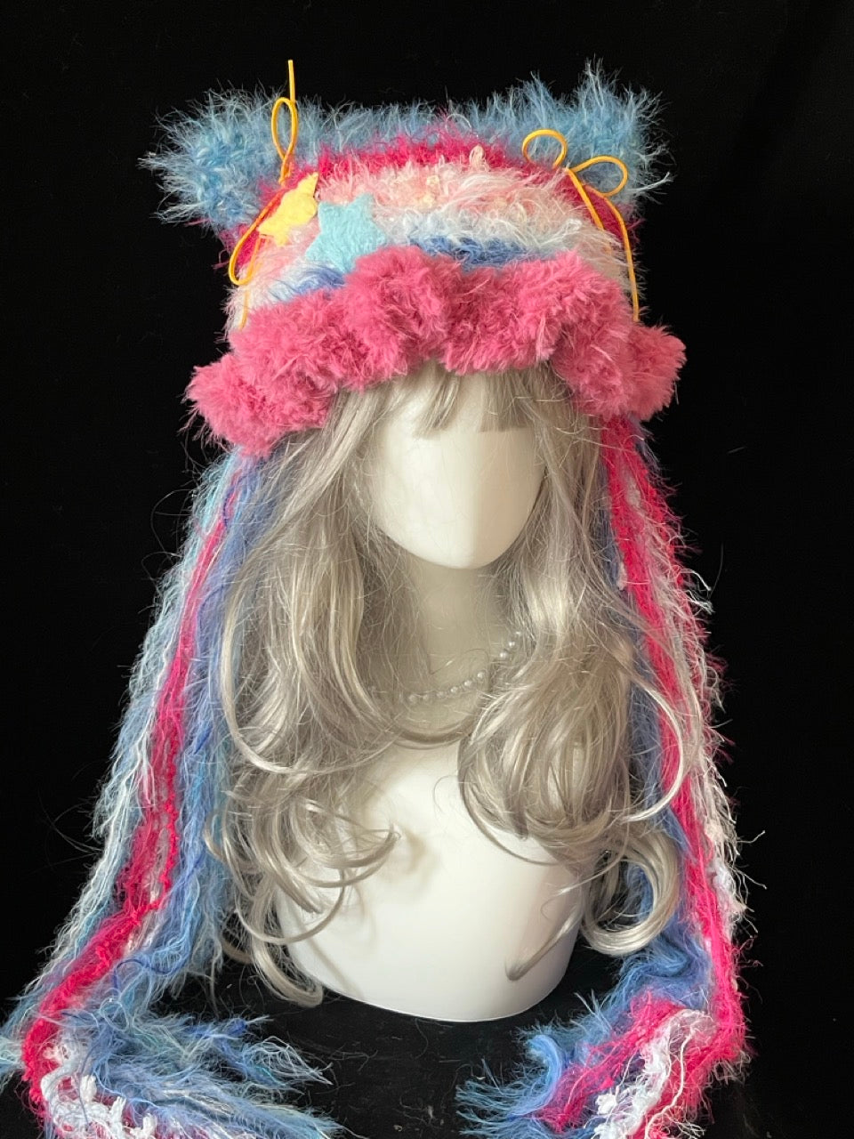 handmade crochet y2k pastel cat ear hat in pink and blue shaggy texture with yellow star charms and long trailing strands, a festival rave accessory