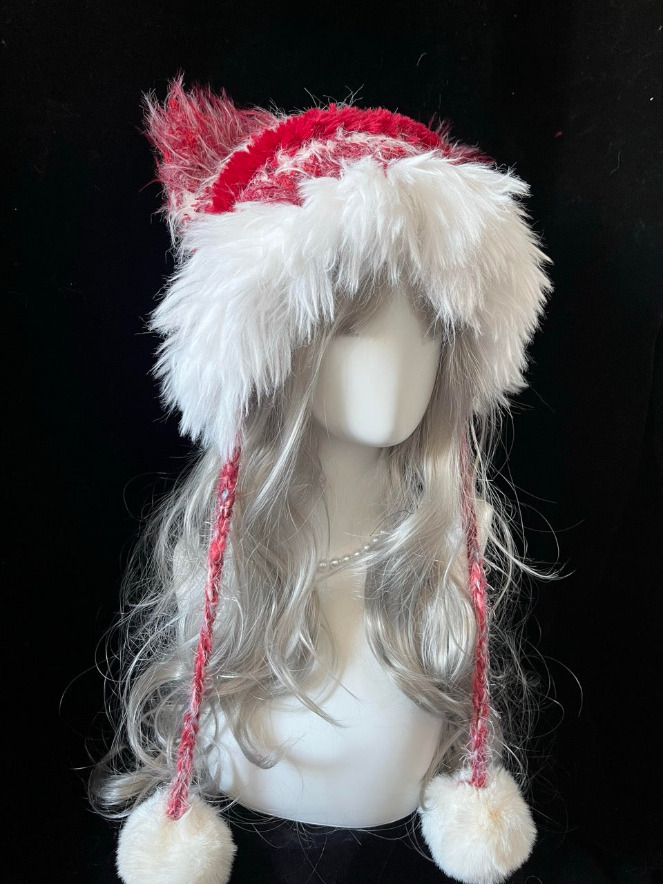 handmade crochet Christmas festive cat ear hat in red and white shaggy texture, with long braided ties and fluffy pompom ends, a holiday winter accessory