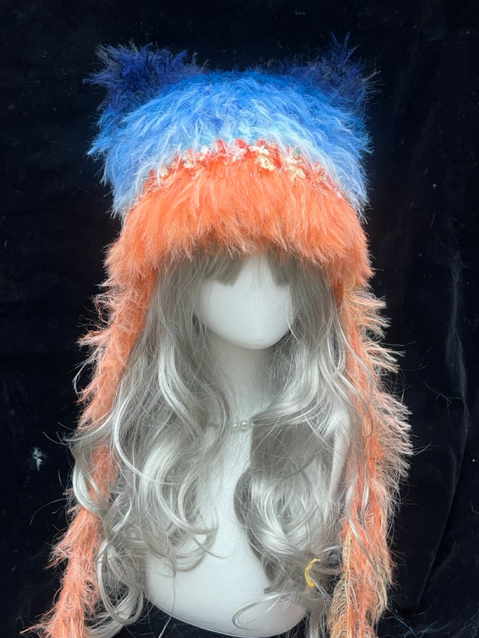 handmade crochet y2k cat ear hat in bright orange and blue shaggy texture, with tall pointed ears and long draped sides, a statement rave and festival accessory