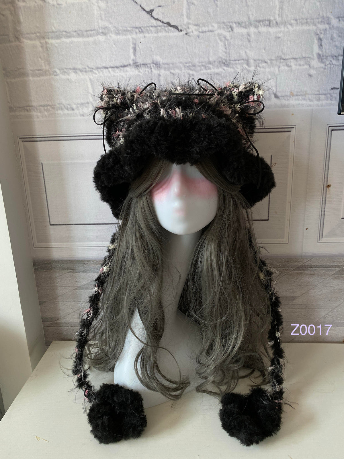 handmade crochet goth coquette cat ear hat in black and pink floral textured yarn with pointed ears and plush pompom ties. Whimsical cosplay headwear for rave party and winter photoshoots