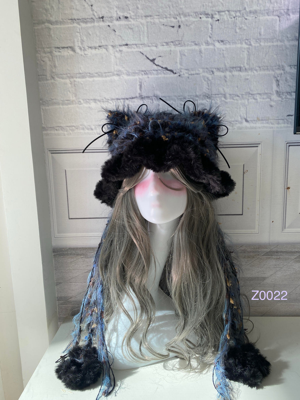 handmade crochet goth dark fairy cat ear hat in black and blue mixed fluffy texture with pointed ears and plush pompom ends. Whimsical cosplay headwear for rave party and winter photoshoots