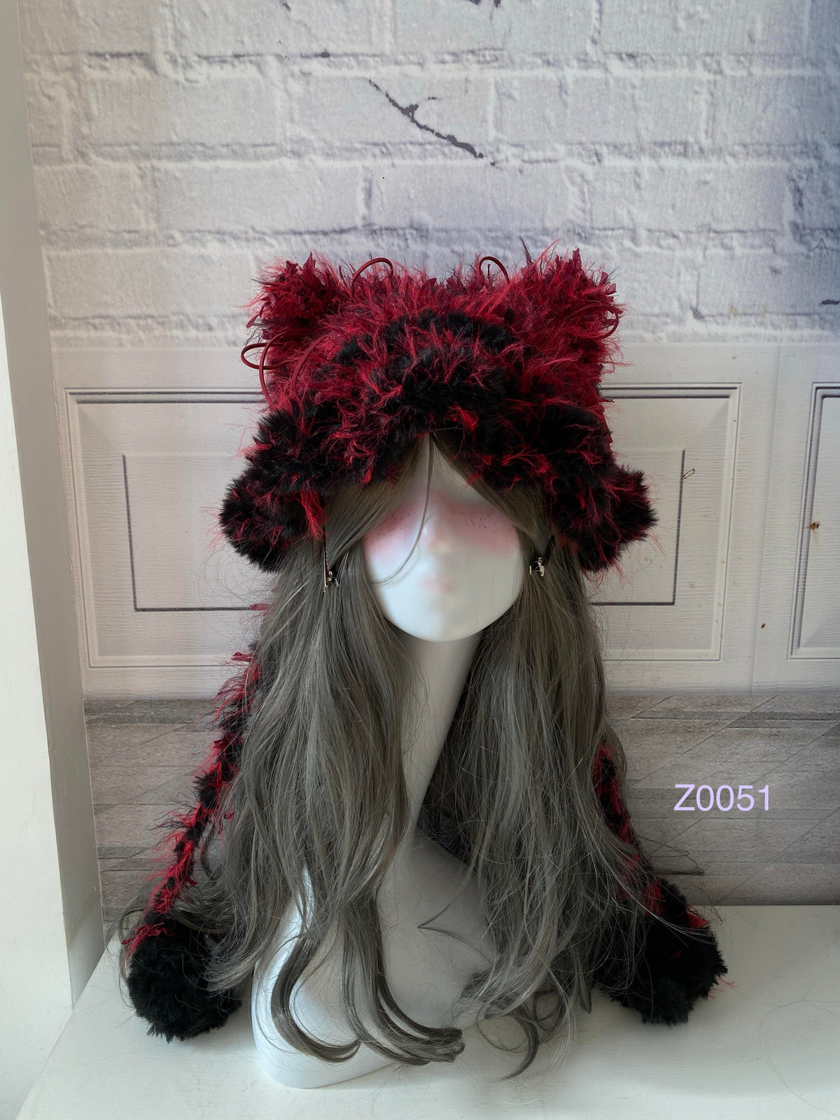 handmade crochet goth dark fairy cat ear hat in black and red fluffy contrast with pointed ears and black pompom ends. Whimsical cosplay headwear for rave party and winter photoshoots
