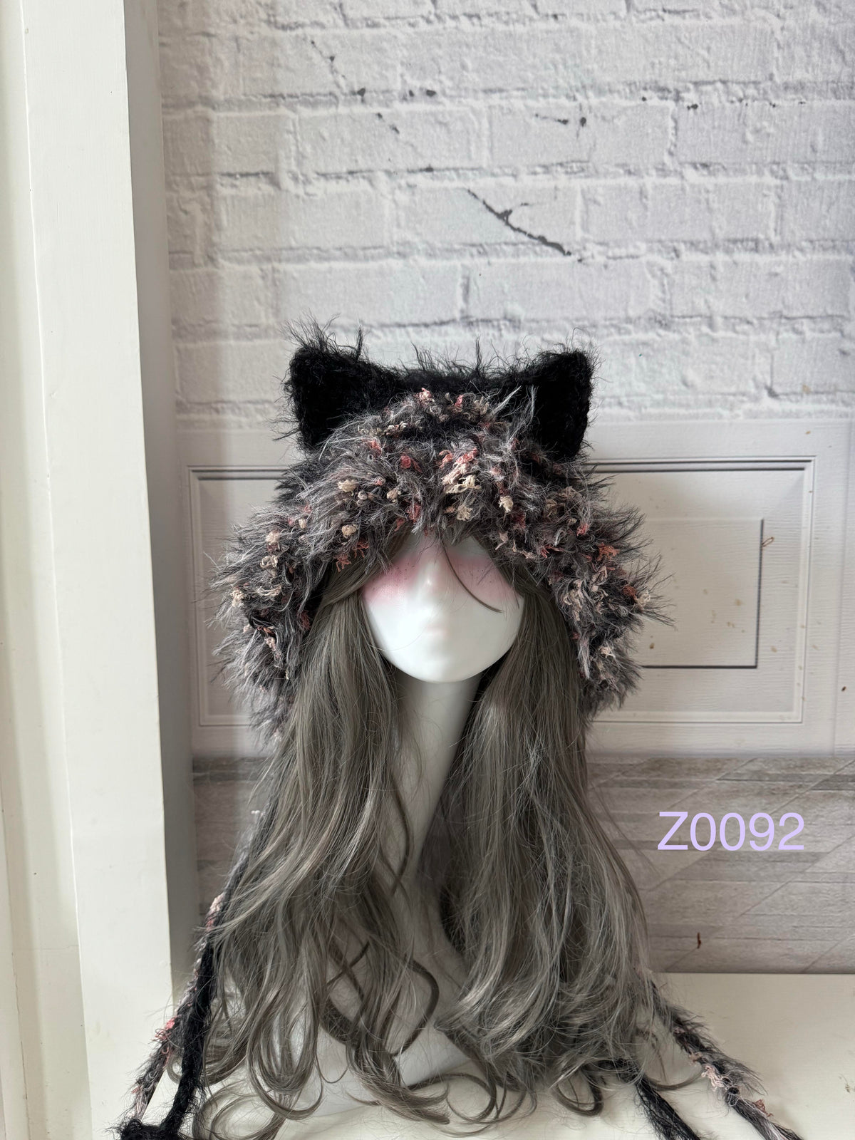 handmade crochet dark fairy goth cat ear hood in black and pink floral textured yarn with pointed ears and long trailing ties. Whimsical cosplay headwear for rave party and winter photoshoots