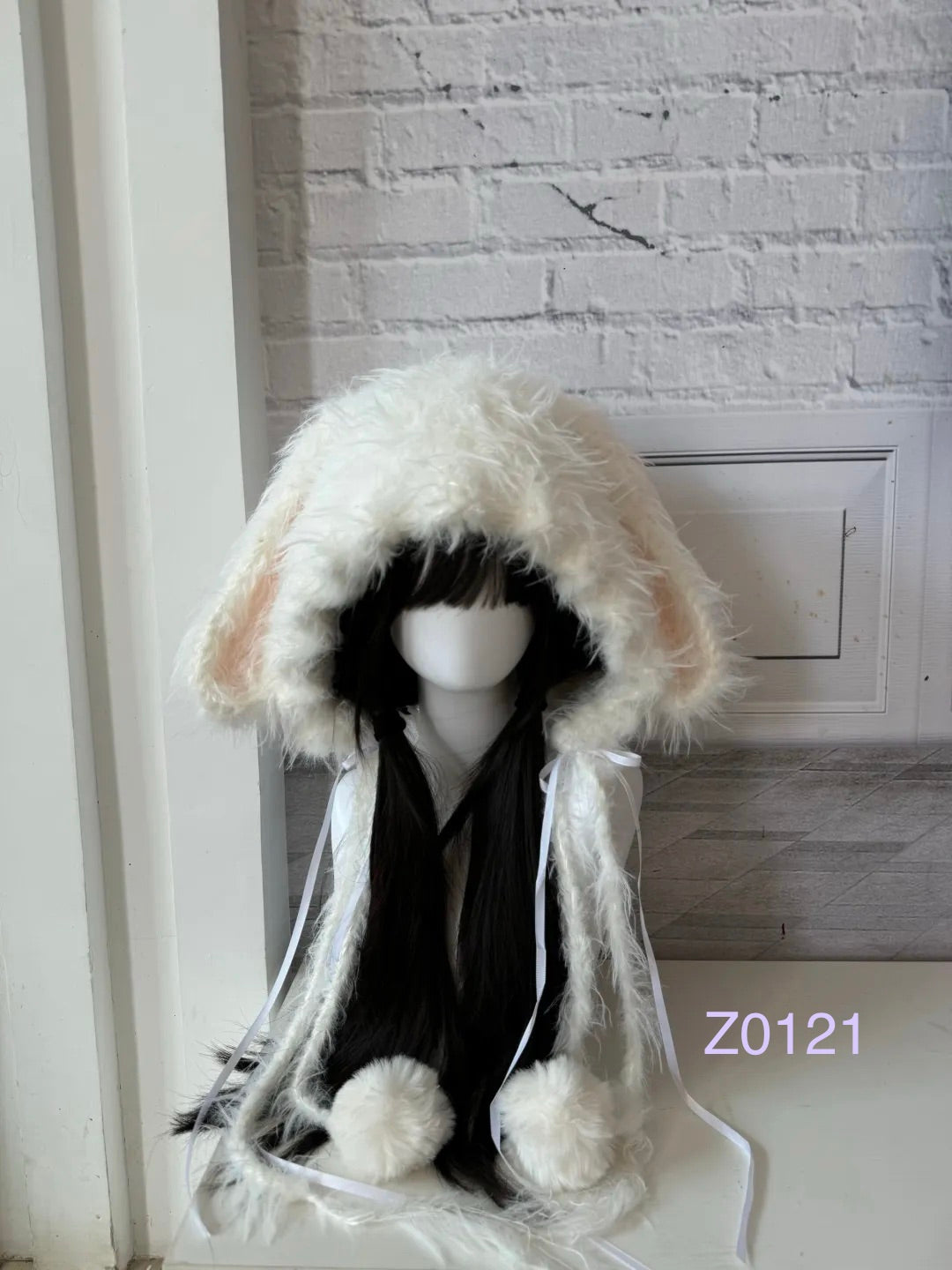 handmade crochet coquette kawaii bunny ear hood in fluffy cream with soft pink inner ears, white satin ribbons and plush pompom ties. Cozy winter headwear for cosplay, photoshoot prop and gift idea
