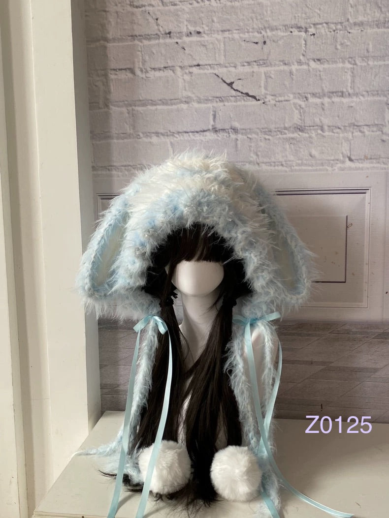 handmade crochet kawaii fairycore bunny ear hood in soft ice blue and white fluffy texture, light blue satin ribbons and white pompom ends. Cozy winter headwear for cosplay, photoshoot prop and gift idea