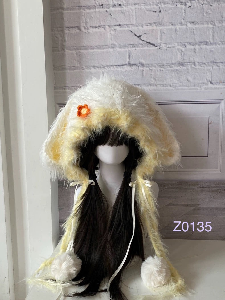 handmade crochet cottagecore fairycore bunny ear hood in soft cream and yellow fluffy texture with a small orange flower detail, white satin ribbons and pompom ends. Whimsical woodland headwear for cosplay, photoshoot prop and gift giving