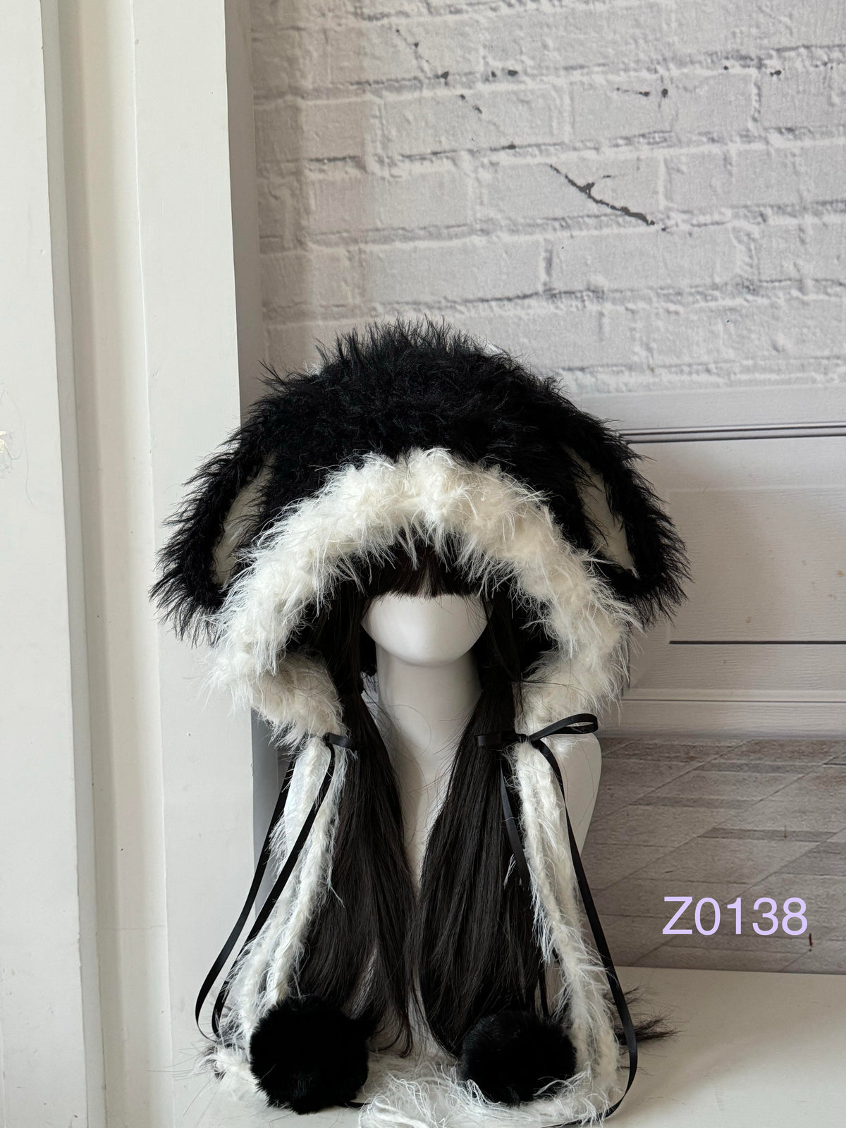 handmade crochet goth monochrome bunny ear hood with bold black and white fluffy contrast, black satin ribbons and fur pompom ends. Dark fairy headwear for cosplay, party and photoshoot styling