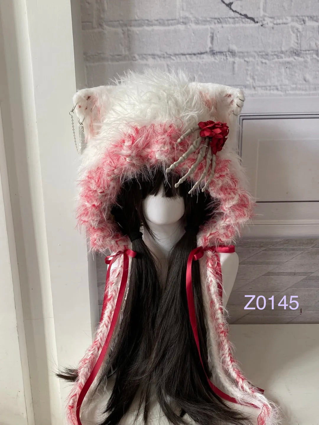 handmade crochet Halloween goth cat ear hood in white and pink fluffy texture with skeleton hand and red rose details, red satin ribbons and long trailing ties. Dark fairy headwear for cosplay, Halloween party and photoshoot styling