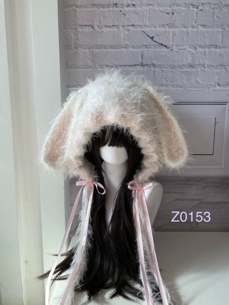 handmade crochet coquette dollette bunny ear hood in soft cream and pale pink fluffy texture, pink satin ribbon bows and long trailing ties. Sweet fairycore headwear for cosplay, winter festival and romantic photoshoots