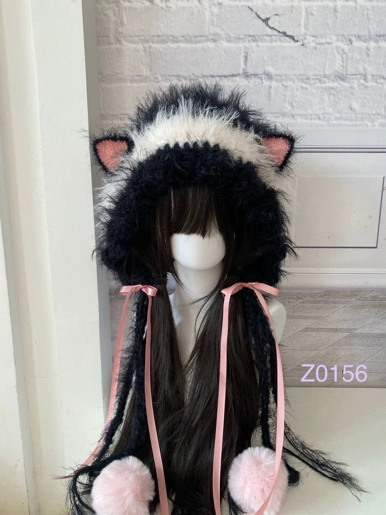 handmade crochet goth coquette cat ear hood with bold black and white fluffy contrast, pink inner ears, pink satin ribbon bows and soft pompom ties. Kawaii cosplay headwear for photoshoot prop and gift idea