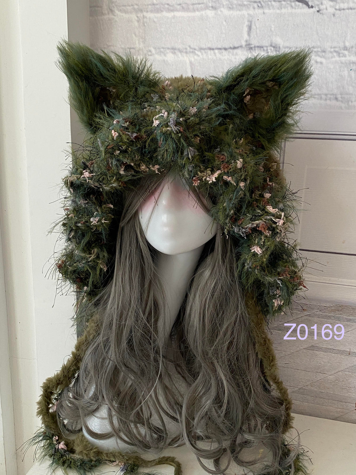 handmade crochet goblincore woodland fox ear hood in dark green moss and floral textured yarn with tall pointed ears and long trailing strands. Cottagecore headwear for cosplay, music festival and photoshoot styling