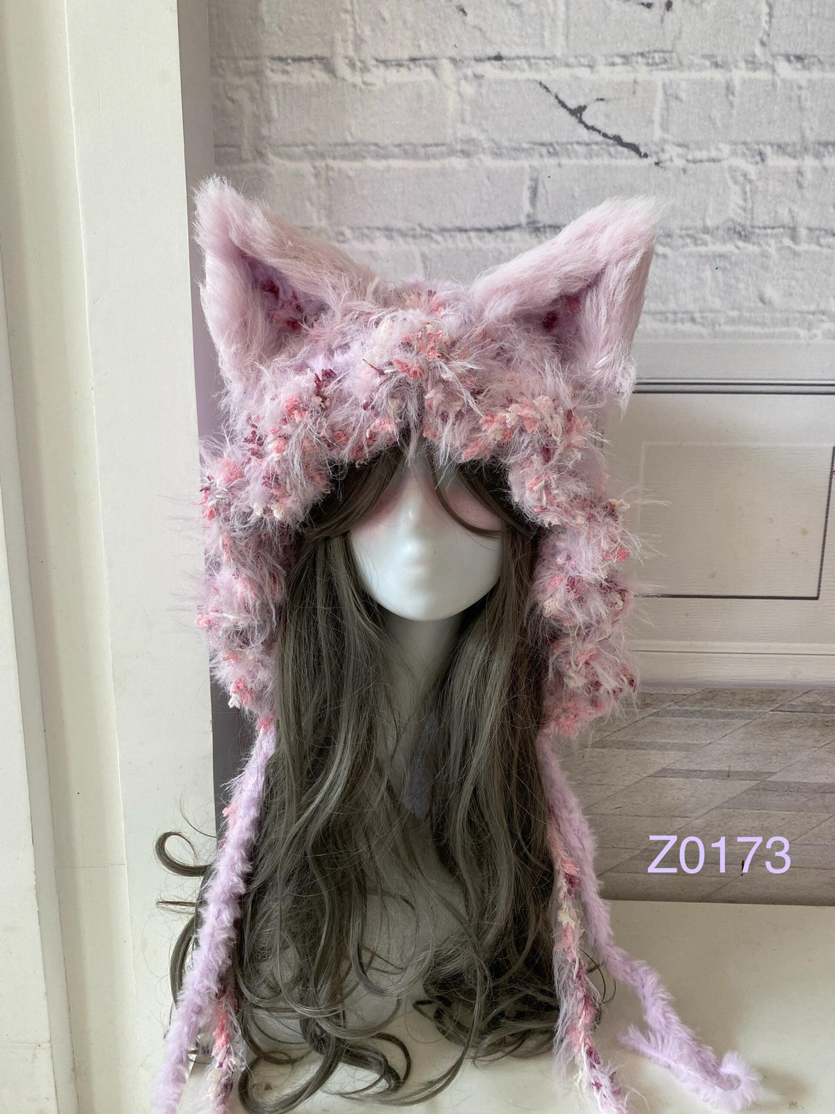 handmade crochet coquette dollette fox ear hood in soft pink floral textured yarn with pointed ears and long trailing ties. Fairycore headwear for cosplay, photoshoot prop and romantic winter styling