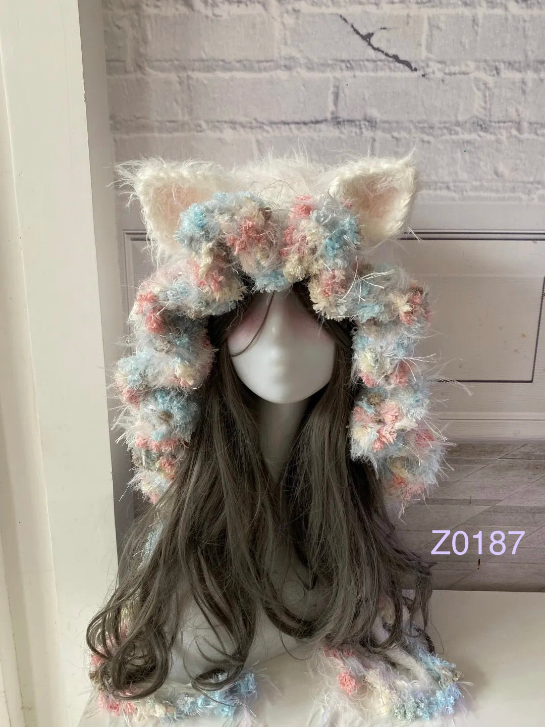 handmade crochet fairycore coquette cat ear hood in cream, pink and blue mixed fluffy texture with pointed ears and long trailing ties. Kawaii winter headwear for cosplay, photoshoot prop and gift idea