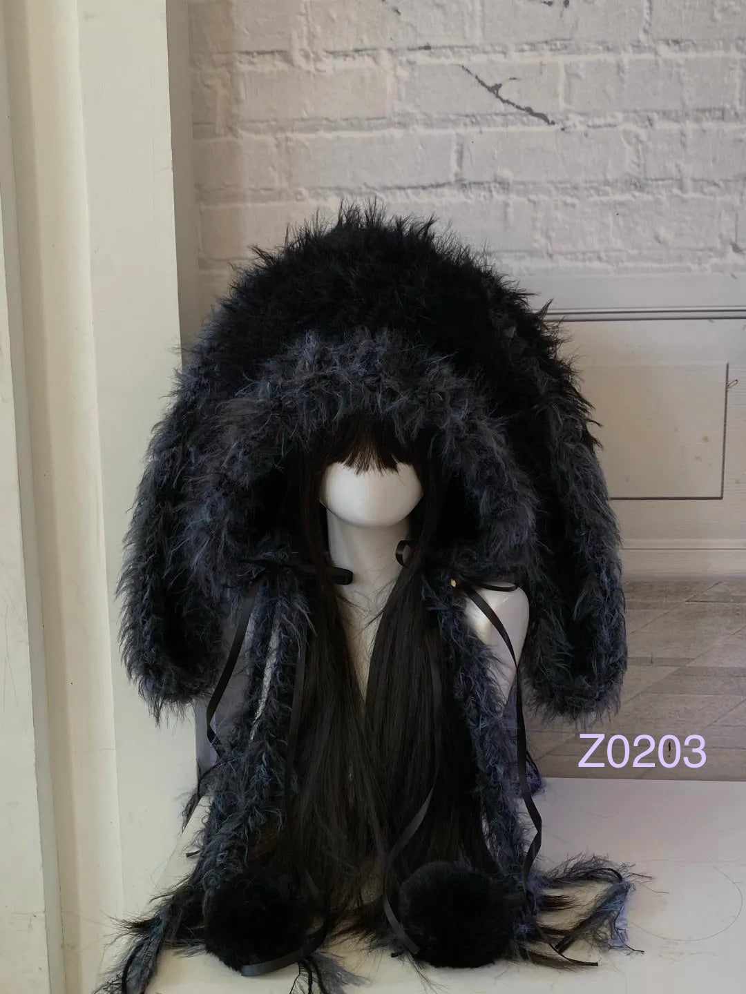 handmade crochet goth dark fairy bunny ear hood in black and blue mixed fluffy texture with long floppy ears, black satin ribbons and plush pompom ties. Whimsical cosplay headwear for rave party and winter photoshoots