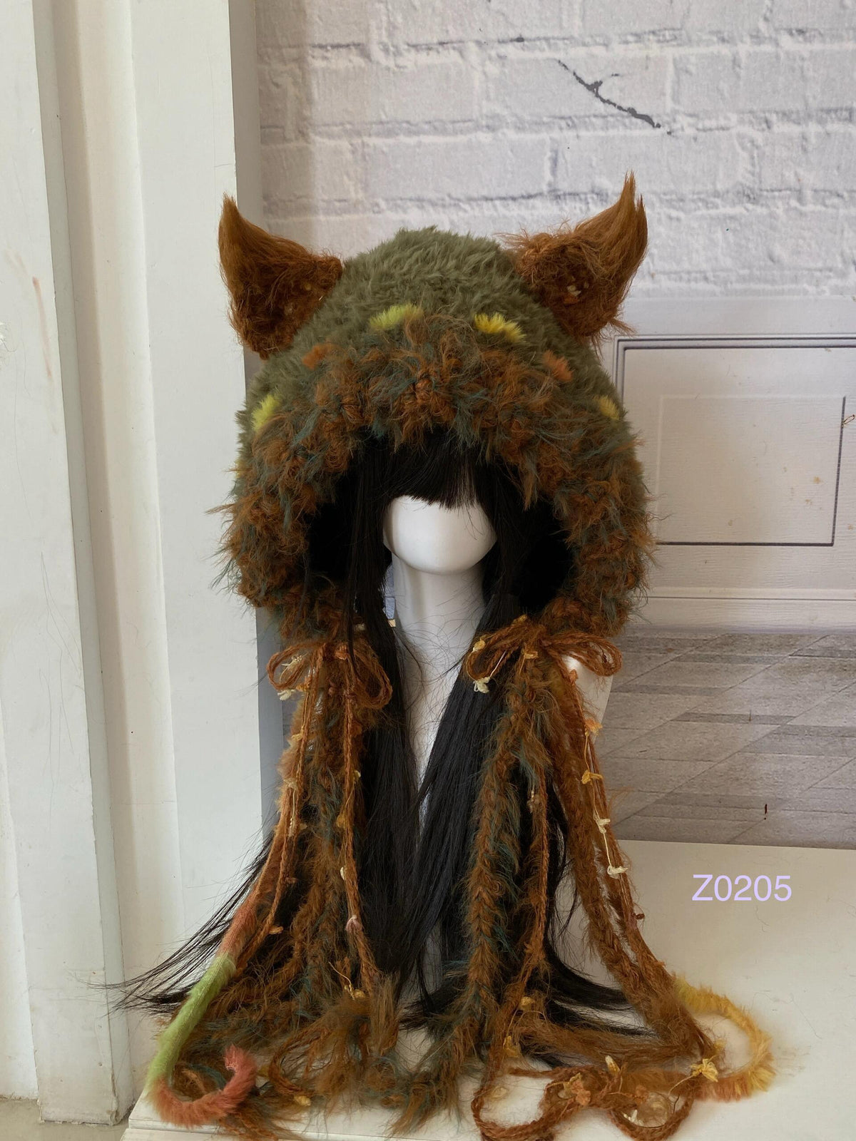 handmade crochet goblincore woodland fox ear hood in olive green, orange and brown textured yarn with pointed ears and long trailing strands. Cottagecore headwear for cosplay, music festival and photoshoot styling