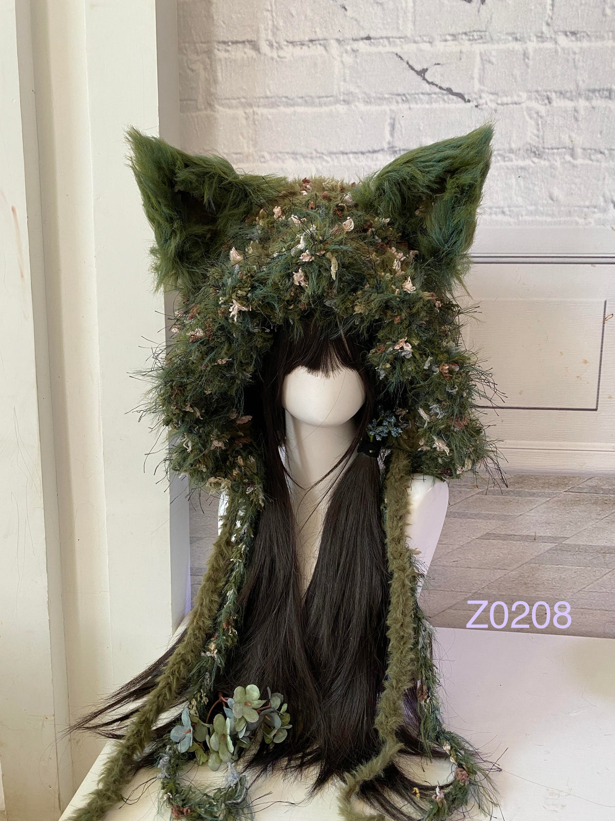 handmade crochet goblincore woodland fox ear hood in dark green moss and floral textured yarn with tall pointed ears and long trailing strands. Cottagecore headwear for cosplay, music festival and photoshoot styling