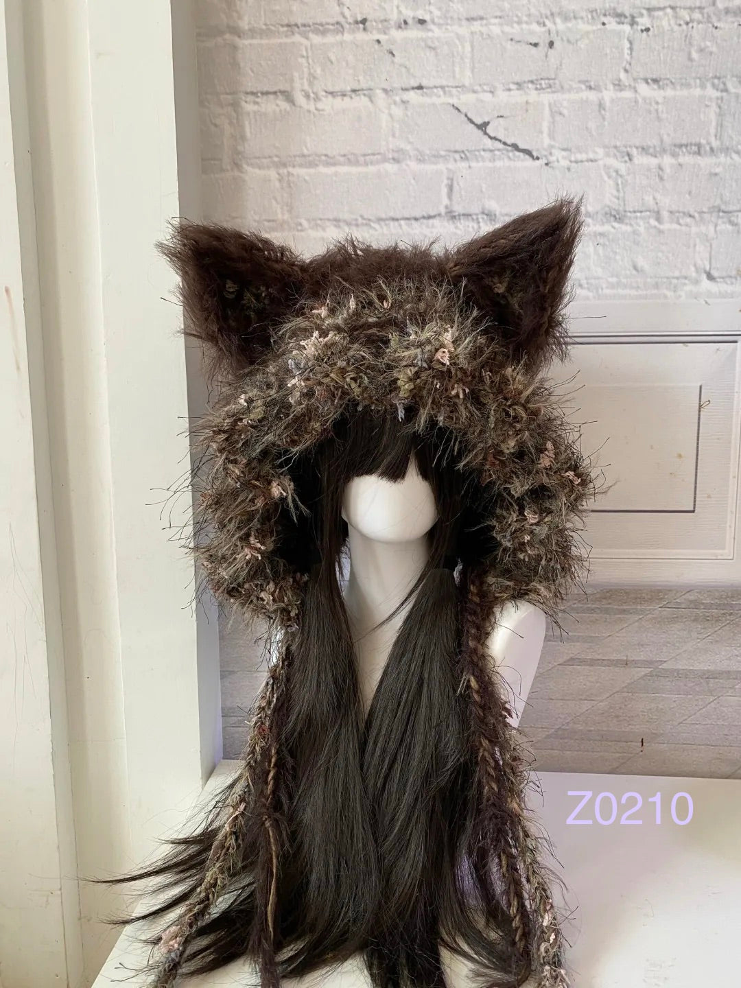 handmade crochet woodland mori girl fox ear hood in dark brown floral textured yarn with pointed ears and long trailing strands. Cottagecore headwear for cosplay, winter festival and photoshoot styling