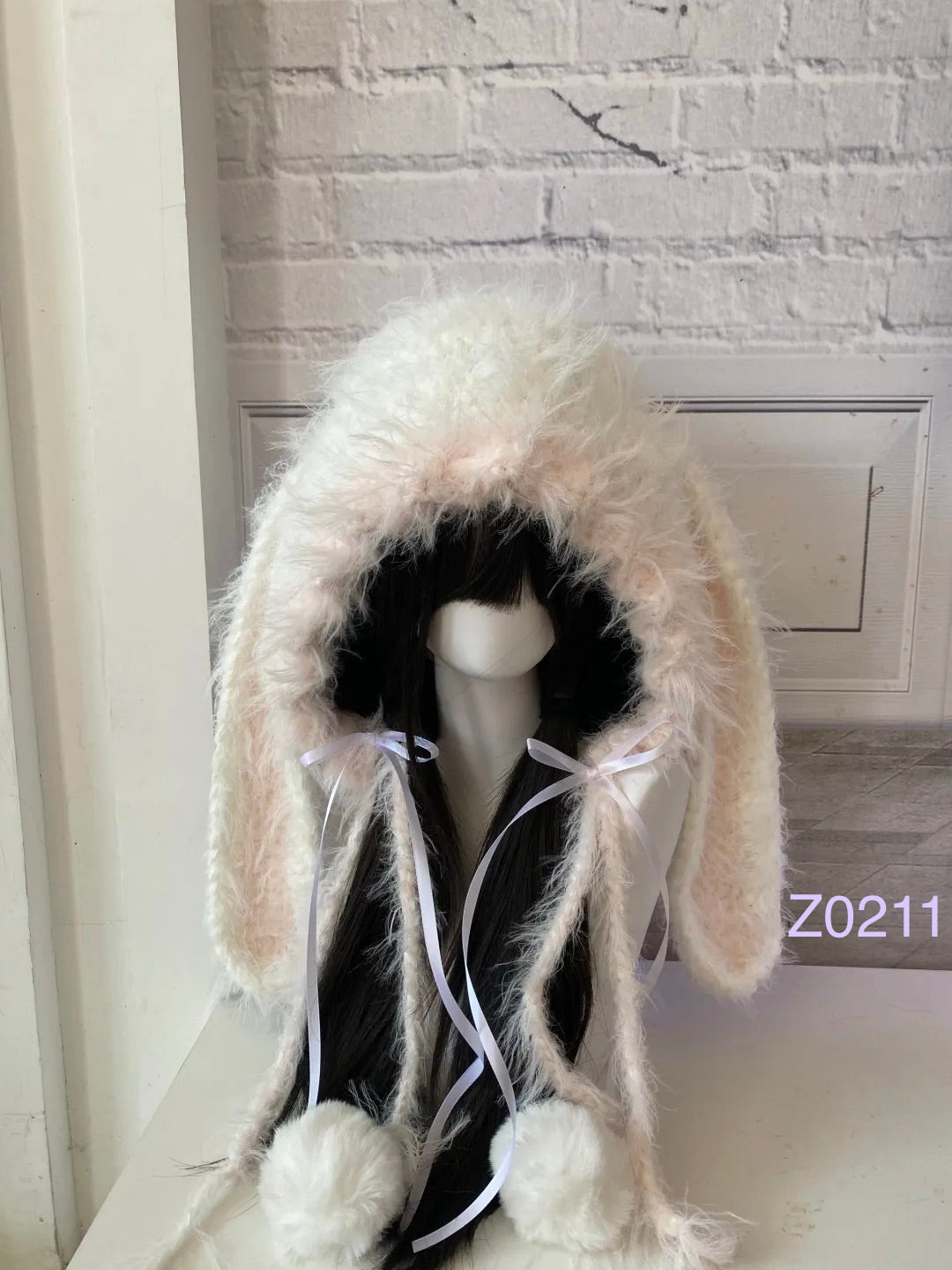 handmade crochet coquette dollette bunny ear hood in soft cream and pale pink fluffy texture, white satin ribbon bows and white pompom ties. Fairycore style headwear for cosplay, photoshoot prop and romantic winter gifting