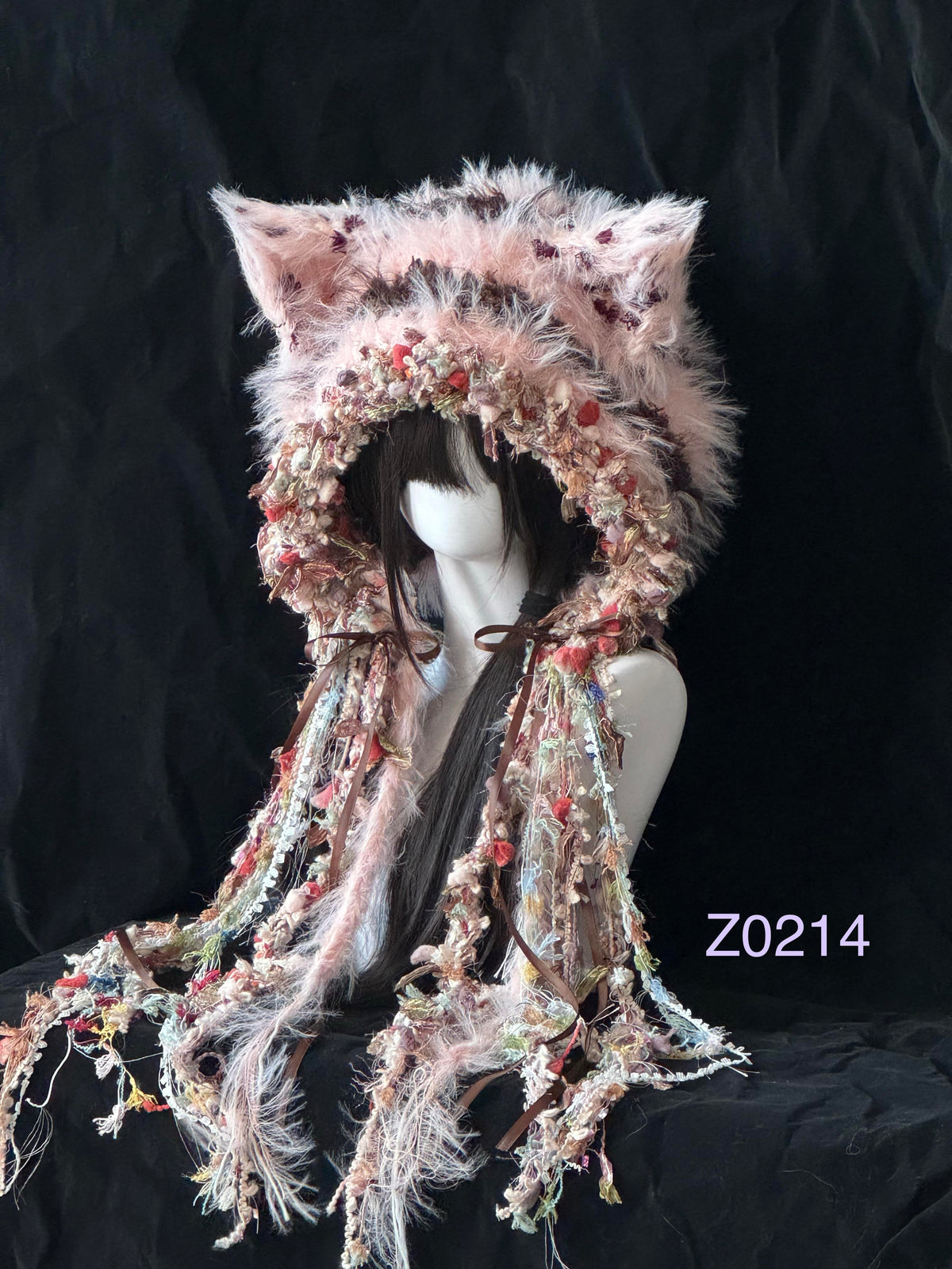 handmade crochet fairycore coquette fox ear hood in pink and brown floral textured yarn with pointed ears, brown satin ribbons and long tassel details. Whimsical headwear for cosplay, photoshoot prop and festival styling