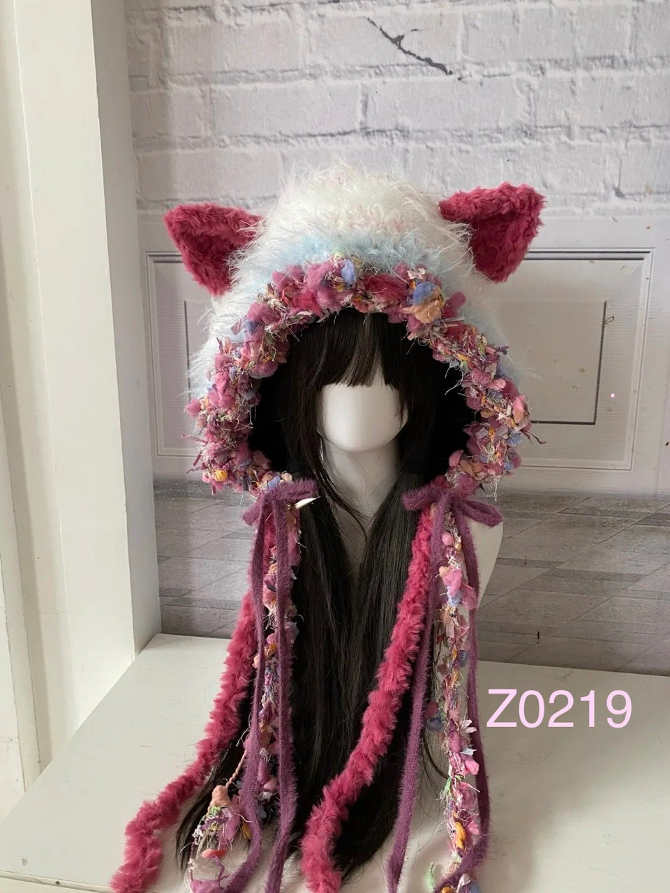 handmade crochet coquette dark fairy cat ear hood in burgundy pink, white and blue floral textured yarn with long trailing ribbons. Whimsical cosplay headwear for party, photoshoot and festival styling
