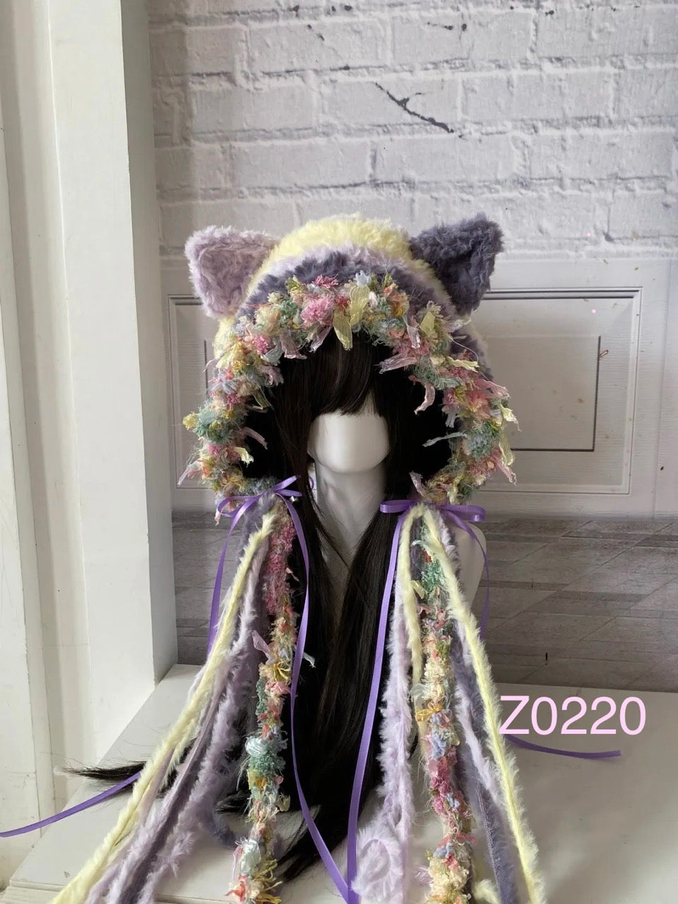 handmade crochet fairycore dollette cat ear hood in purple and yellow pastel floral textured yarn with purple satin ribbon bows and long tassel details. Kawaii headwear for cosplay, photoshoot prop and gift idea