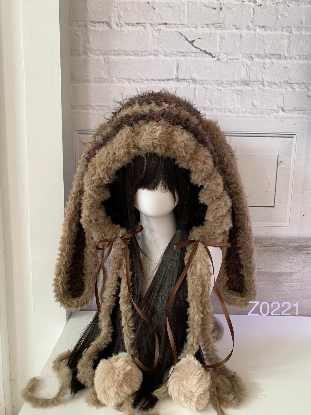handmade crochet woodland cottagecore bunny ear hood in brown and cream fluffy texture with long floppy ears, brown satin ribbons and plush pompom ties. Mori girl style winter headwear for cosplay, festival and photoshoot styling