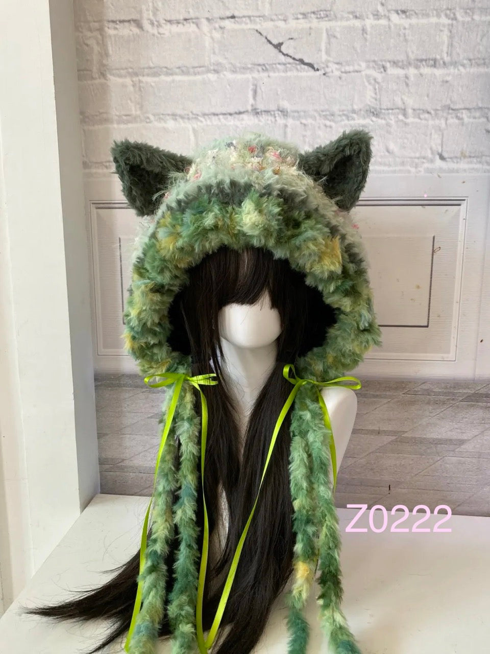 handmade crochet fairycore cottagecore cat ear hood in mint green and soft yellow floral textured yarn with bright green satin ribbon ties and long trailing strands. Whimsical woodland headwear for cosplay, music festival and photoshoot styling