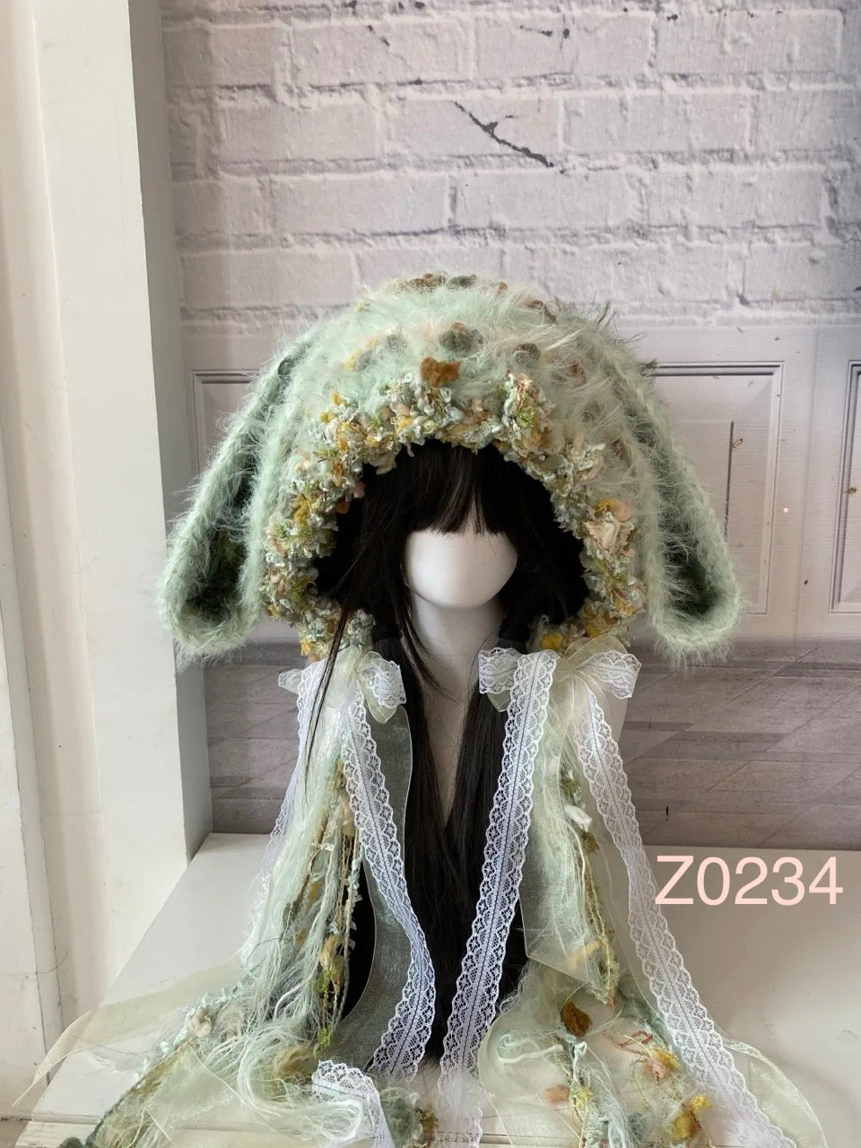 handmade crochet fairycore cottagecore bunny ear hood in mint green floral textured yarn with long floppy ears, white lace ribbons and sheer tulle details. Whimsical woodland headwear for cosplay, photoshoot prop and romantic festival styling