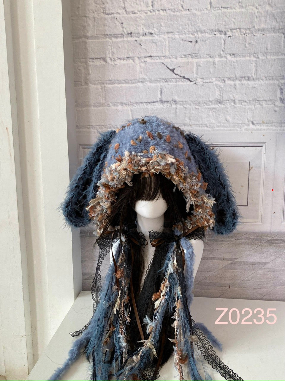 handmade crochet goth cottagecore bunny ear hood in blue gray floral textured yarn with long floppy ears, black lace ribbons and long trailing strands. Dark fairy headwear for cosplay, photoshoot styling and winter festival wear