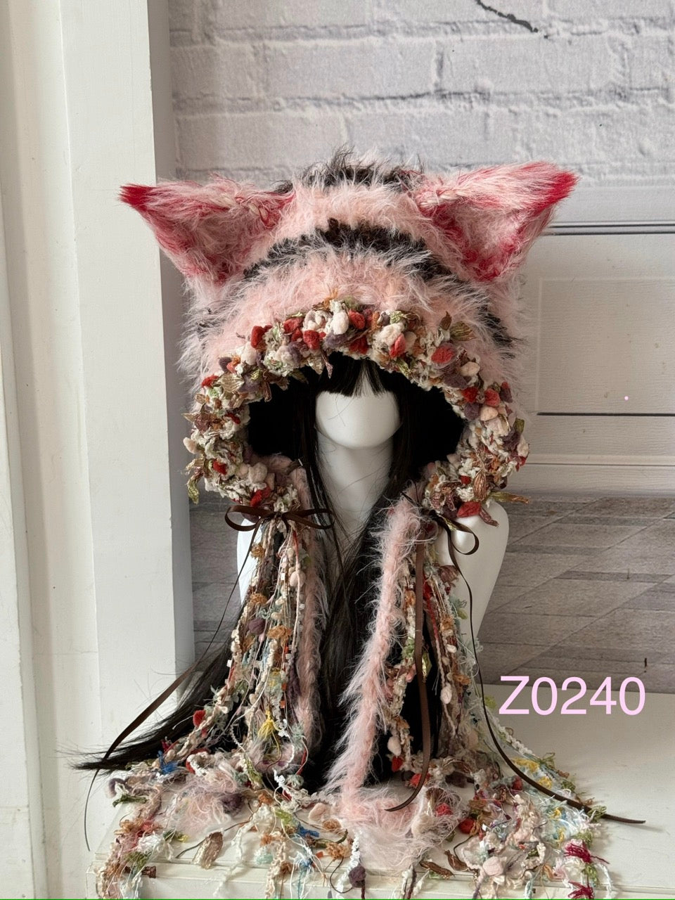 handmade crochet coquette fairycore fox ear hood in pink and red floral textured yarn with tall pointed ears, brown satin ribbons and long trailing details. Dollette headwear for cosplay, photoshoot prop and romantic festival styling