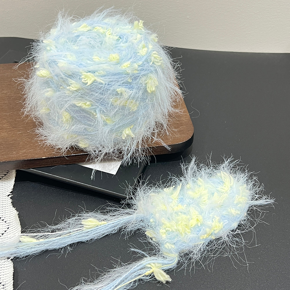 Dreamy misty blue petal bubble cake yarn styled with black frame and lace, pastel textured art yarn