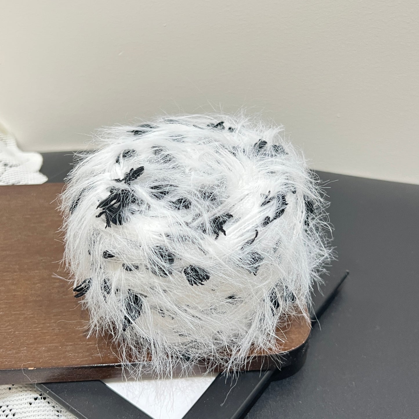 Front overhead round view monochrome black white layered floral hand-blended cake yarn on wooden tray