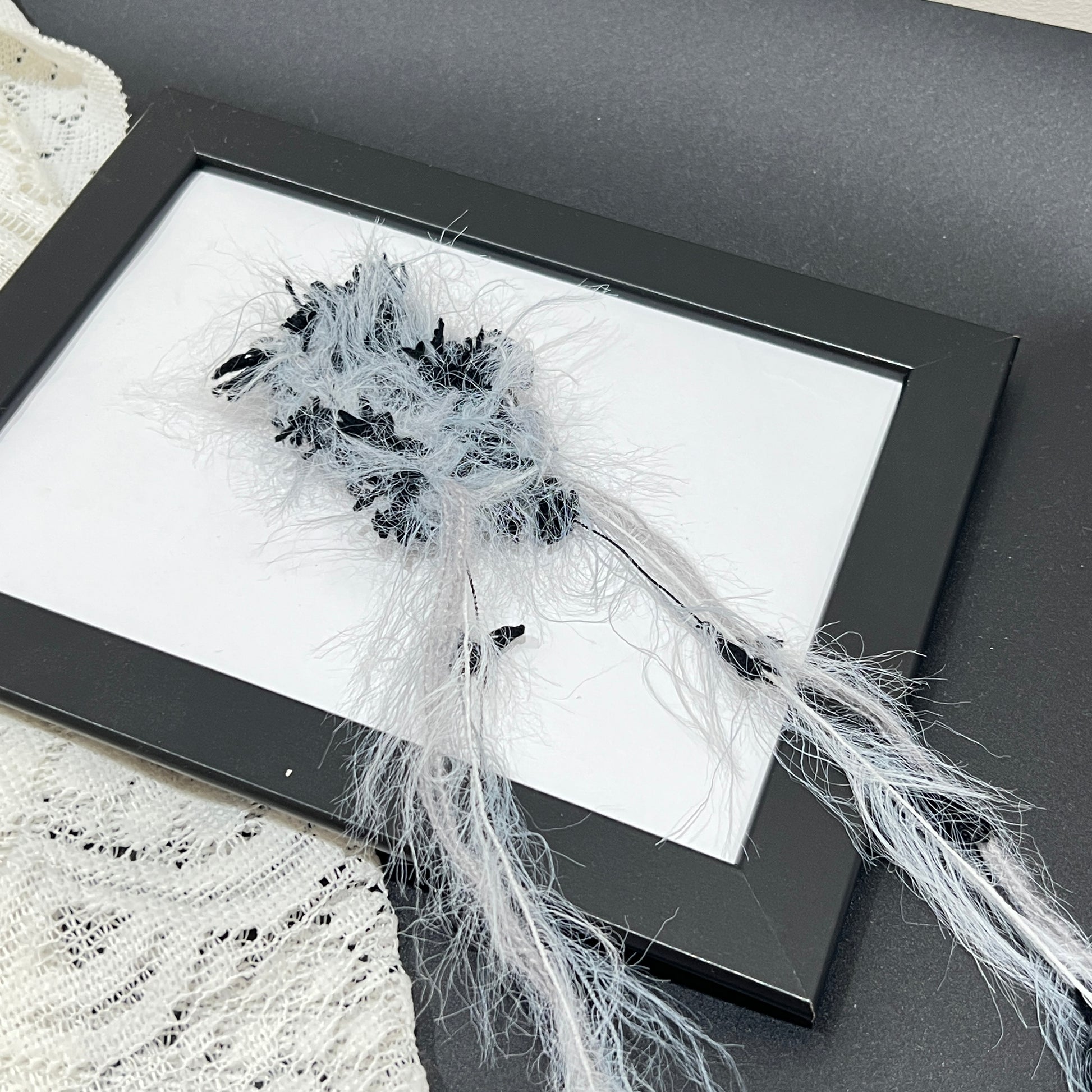 Top-down full round overhead shot gray black floral yarn ball showcasing complete layered airy feather texture