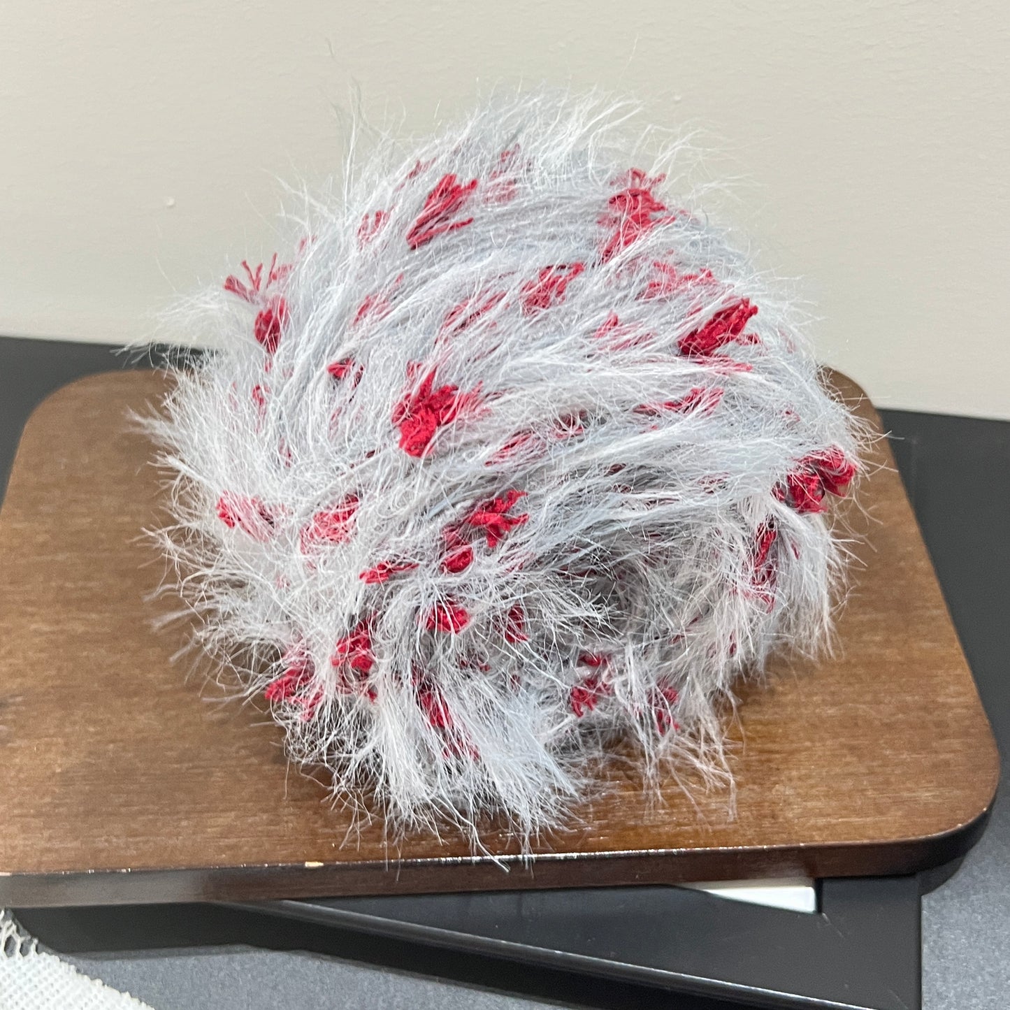 Complete product display set: gray scarlet yarn cake + long-tassel fiber swatch beside white lace fabric on dark tabletop