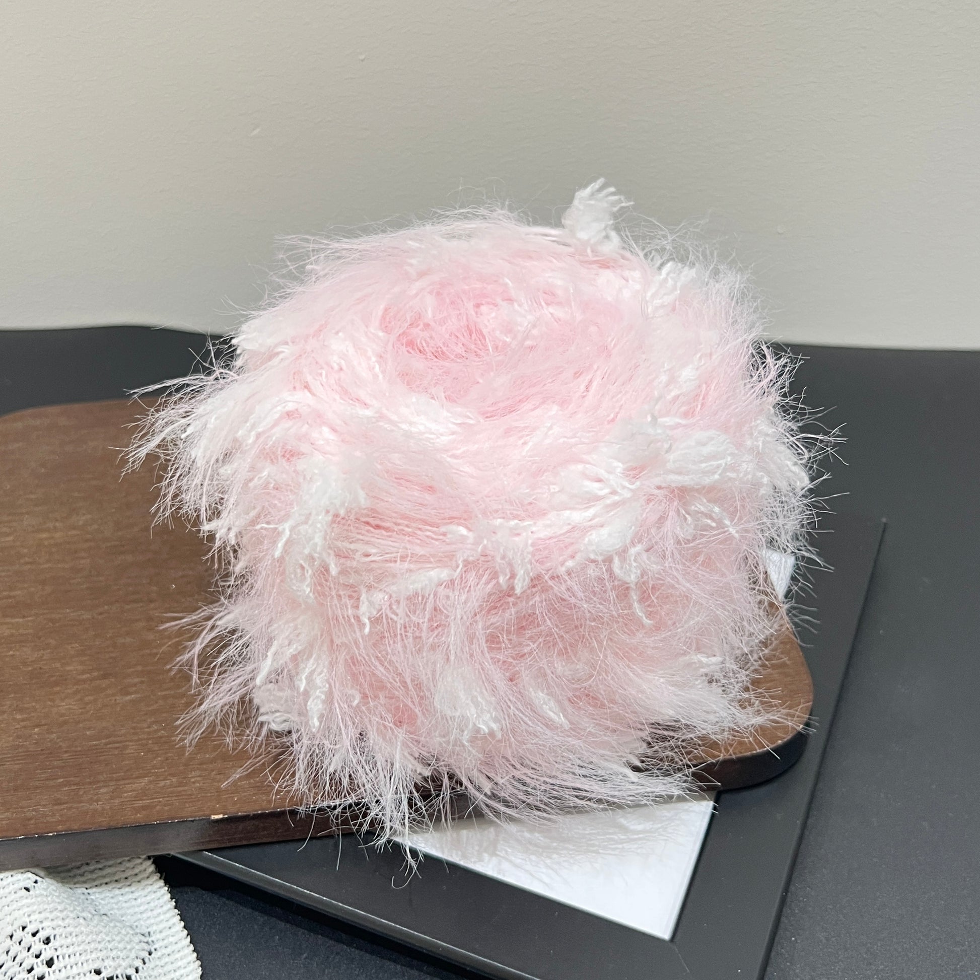 Side round shot pastel blush floral artisan blend yarn cake showing layered fiber texture