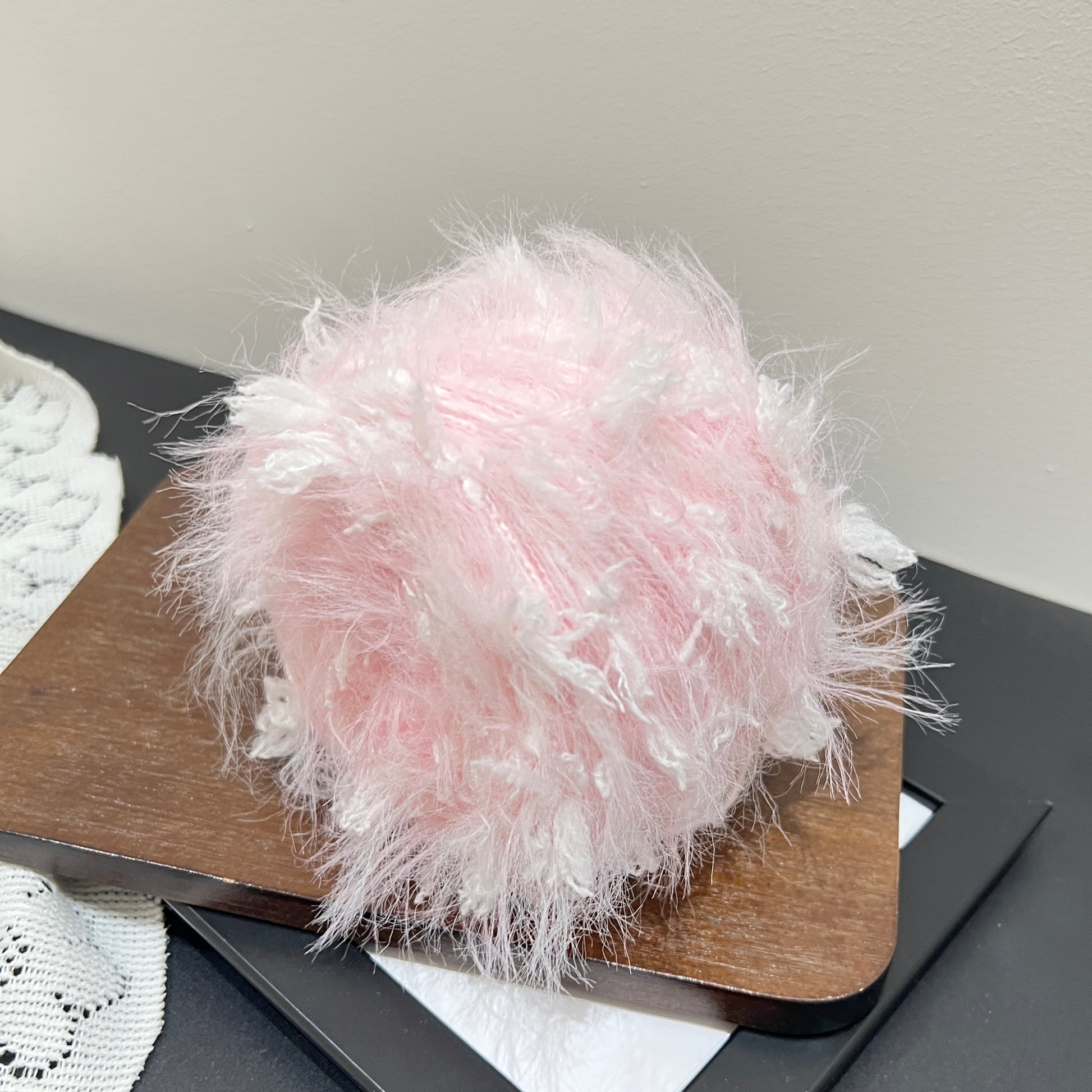Overhead top view pastel blush layered floral hand-blended cake yarn wound as center-pull ball
