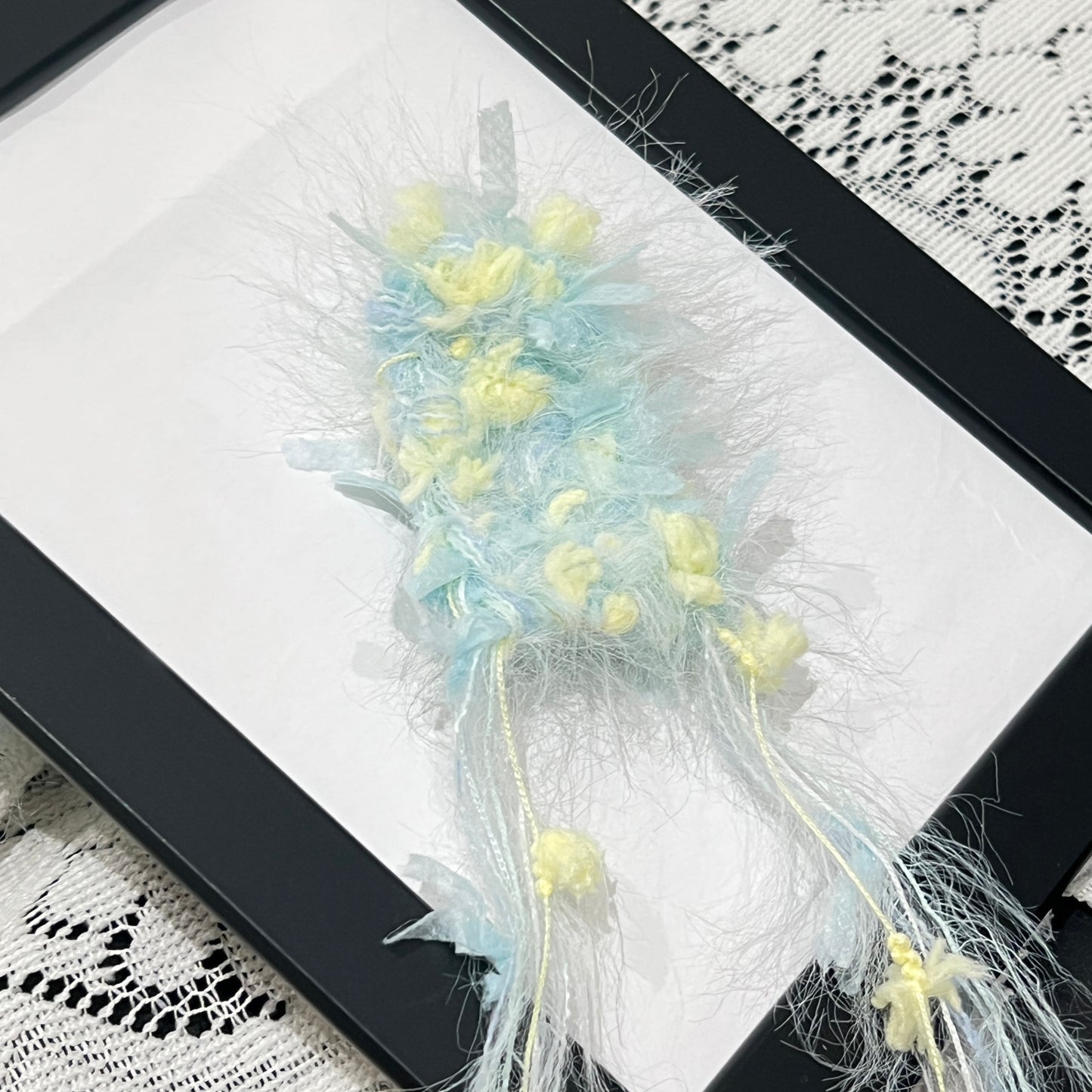 Close-up detail of pastel cyan yellow petal layered multi-strand blended fiber texture with floral strand accents