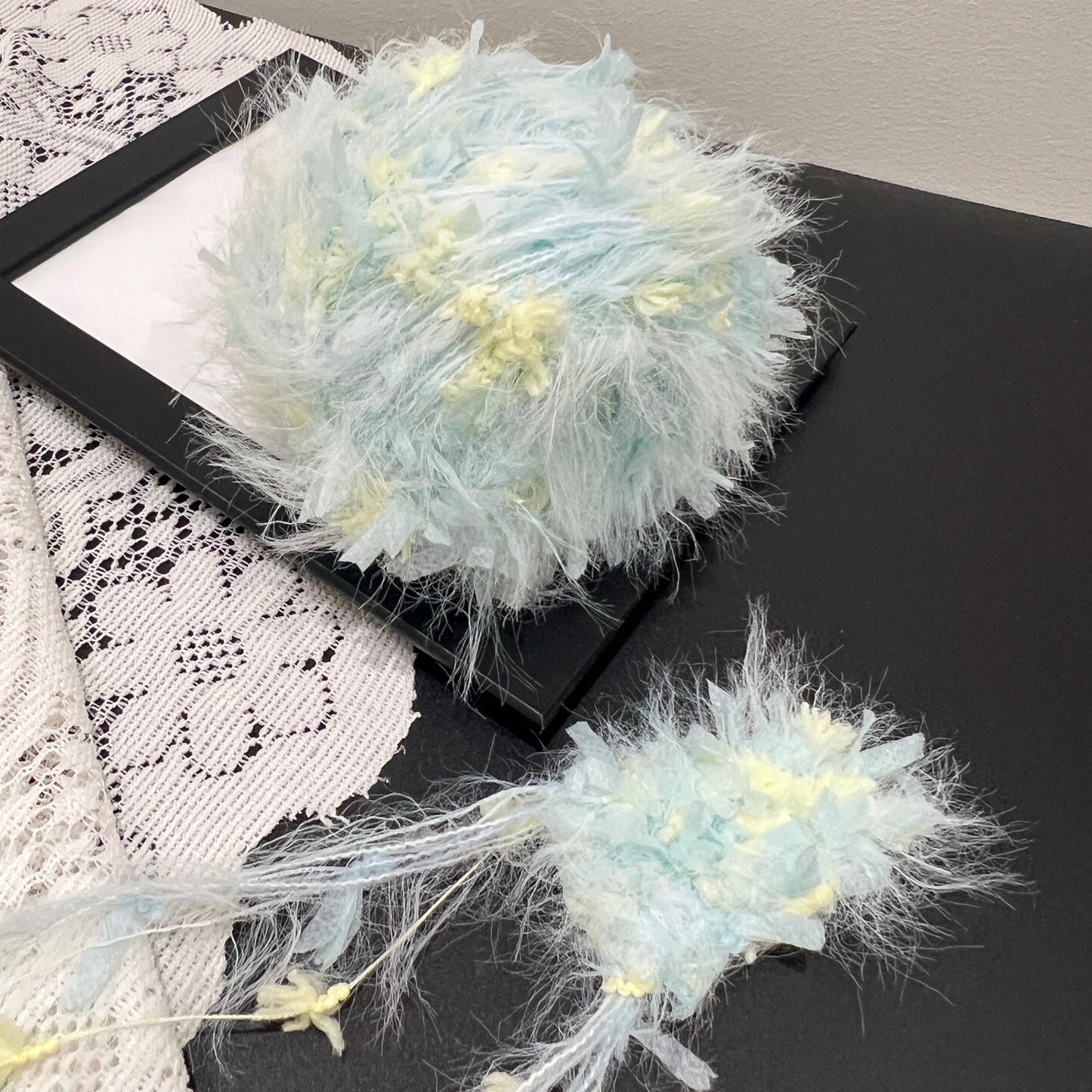 Front overhead round view pastel cyan yellow layered floral hand-blended cake yarn on black display frame
