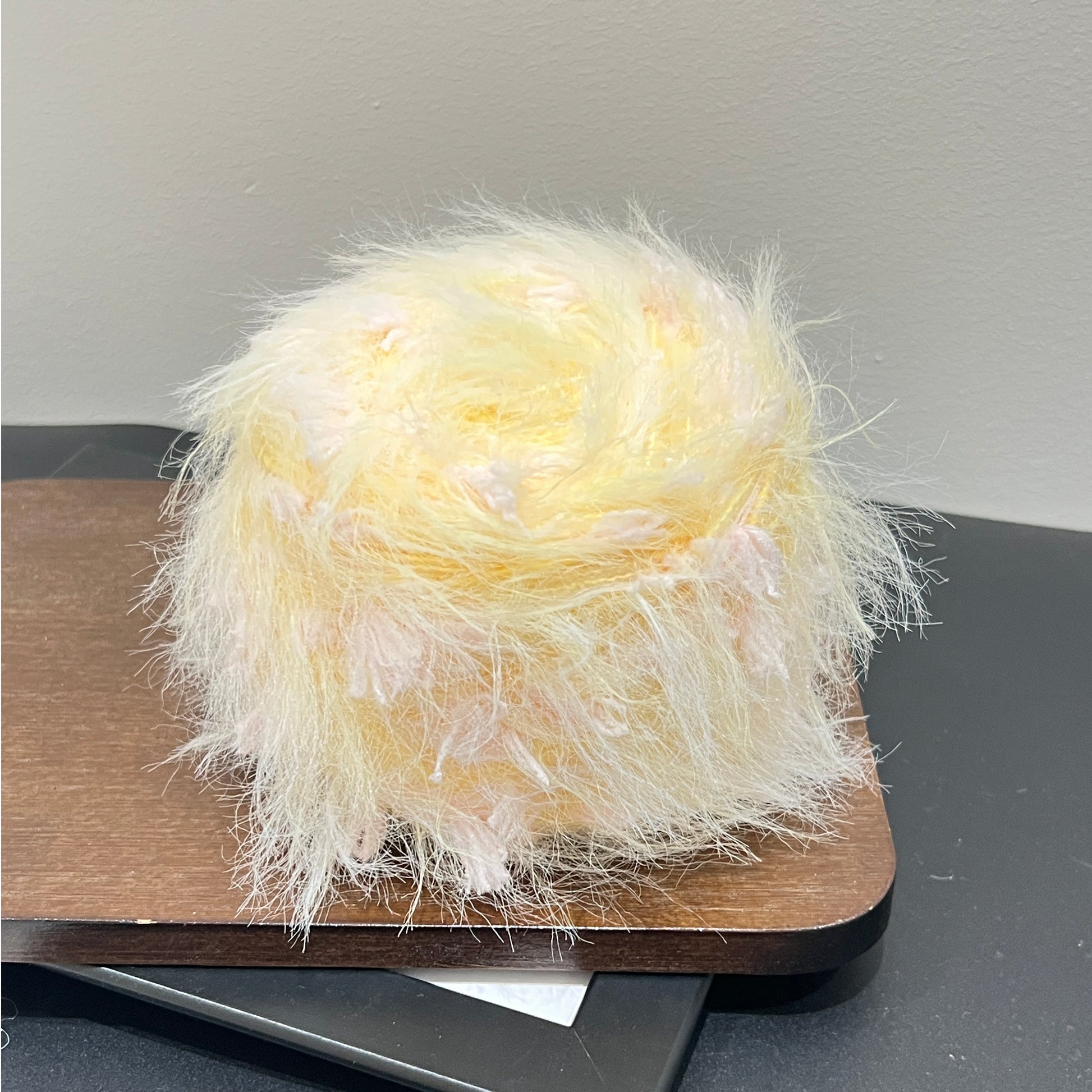 Pastel floral hand-blended yarn cake with fiber swatch on dark countertop