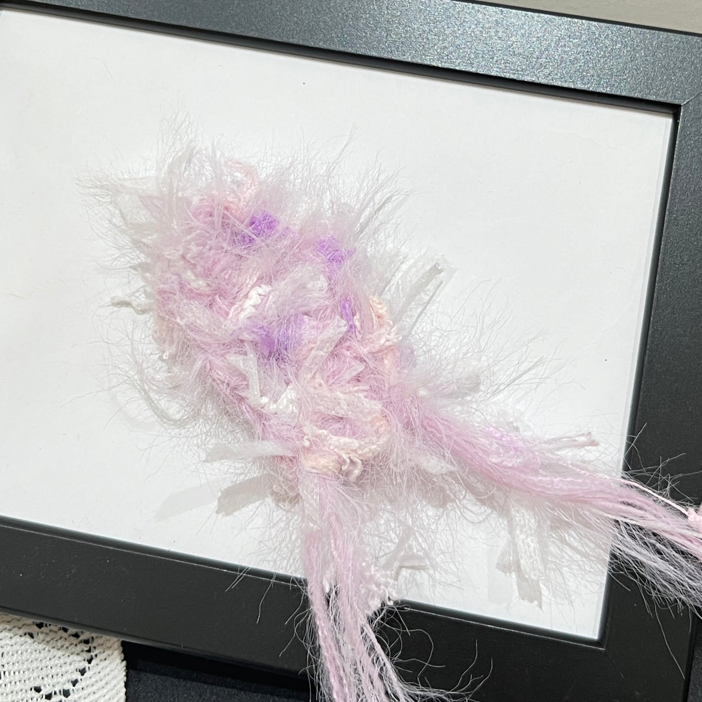 Close-up macro detail of pastel lavender iridescent petal layered multi-strand blended fiber on black display frame