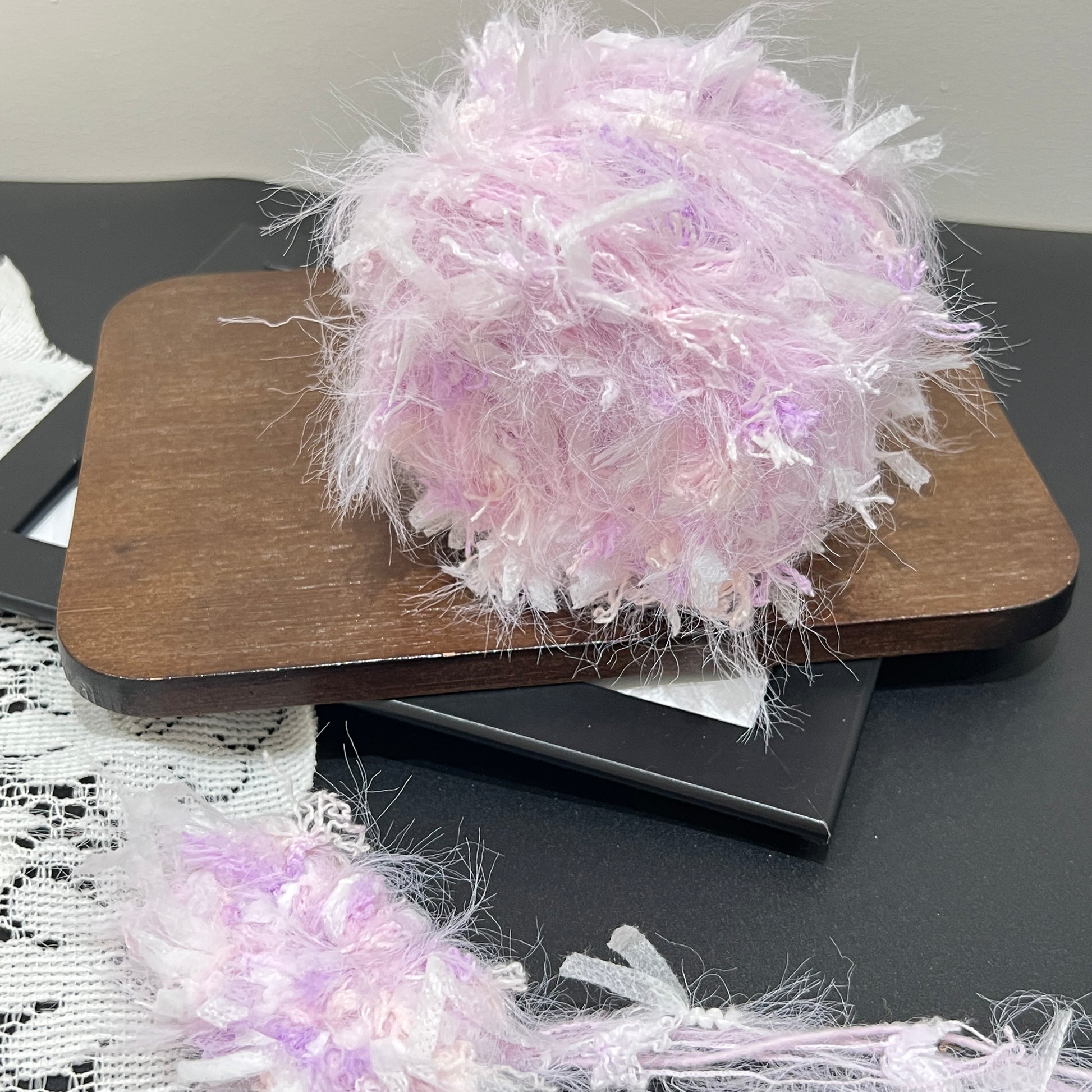 Front overhead round view pastel lavender layered floral hand-blended cake yarn on wooden tray