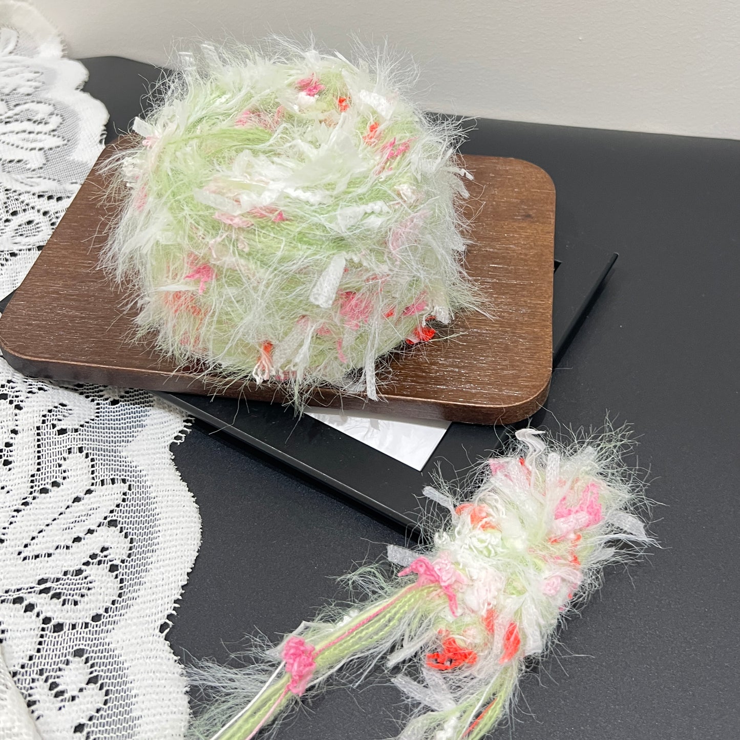 Top-down overhead center view lime multi-tone floral yarn cake showcasing evenly scattered pink, coral and white decorative fiber fragments