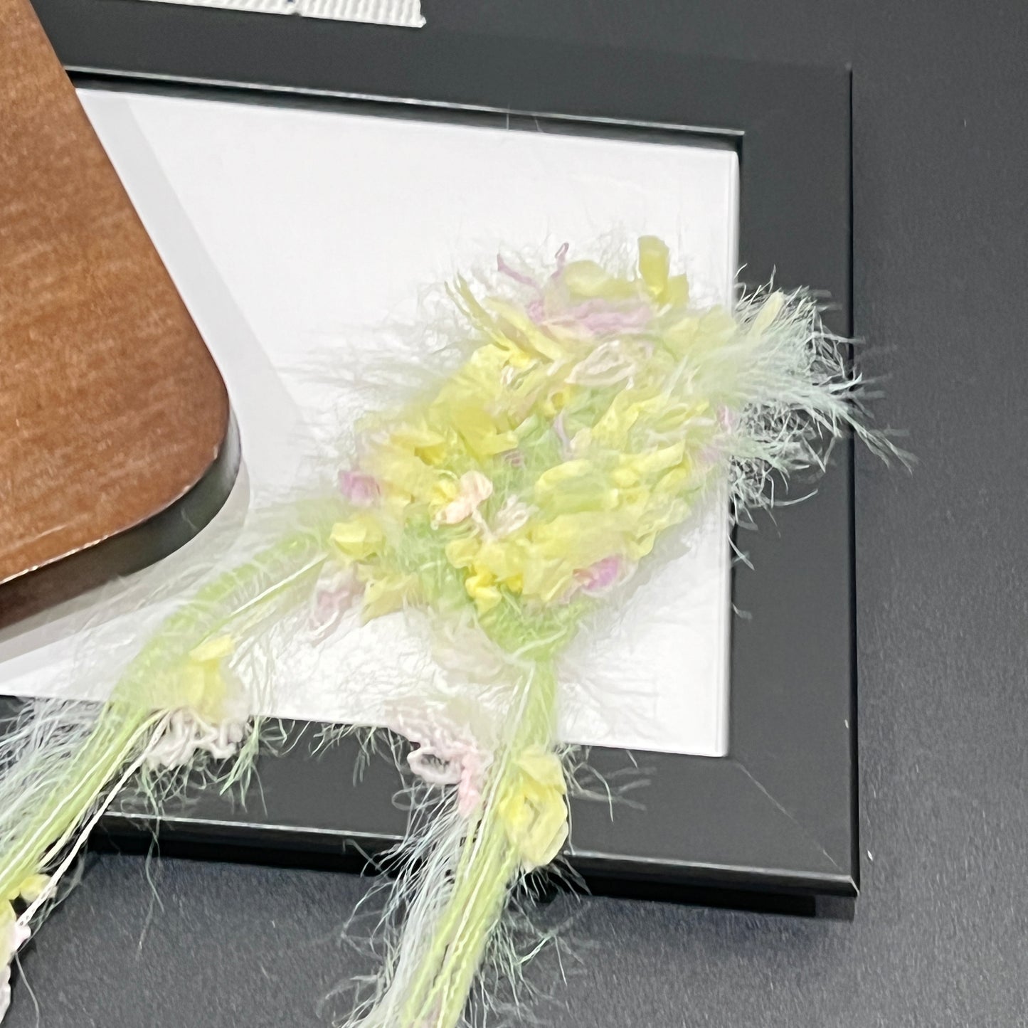Close-up macro detail of pastel lime yellow lilac petal layered multi-strand blended fiber on black frame
